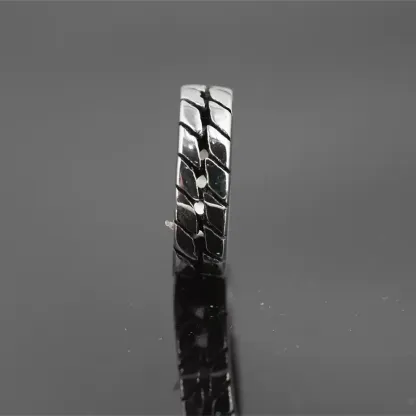 Close-up vertical view of the rugged tire tread pattern on a stainless steel biker ring, reflecting on a dark background.