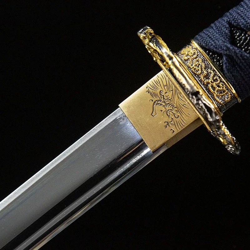 Close-up view of the polished brass habaki blade collar with a detailed hand-engraved dragon design on a high-quality katana sword.