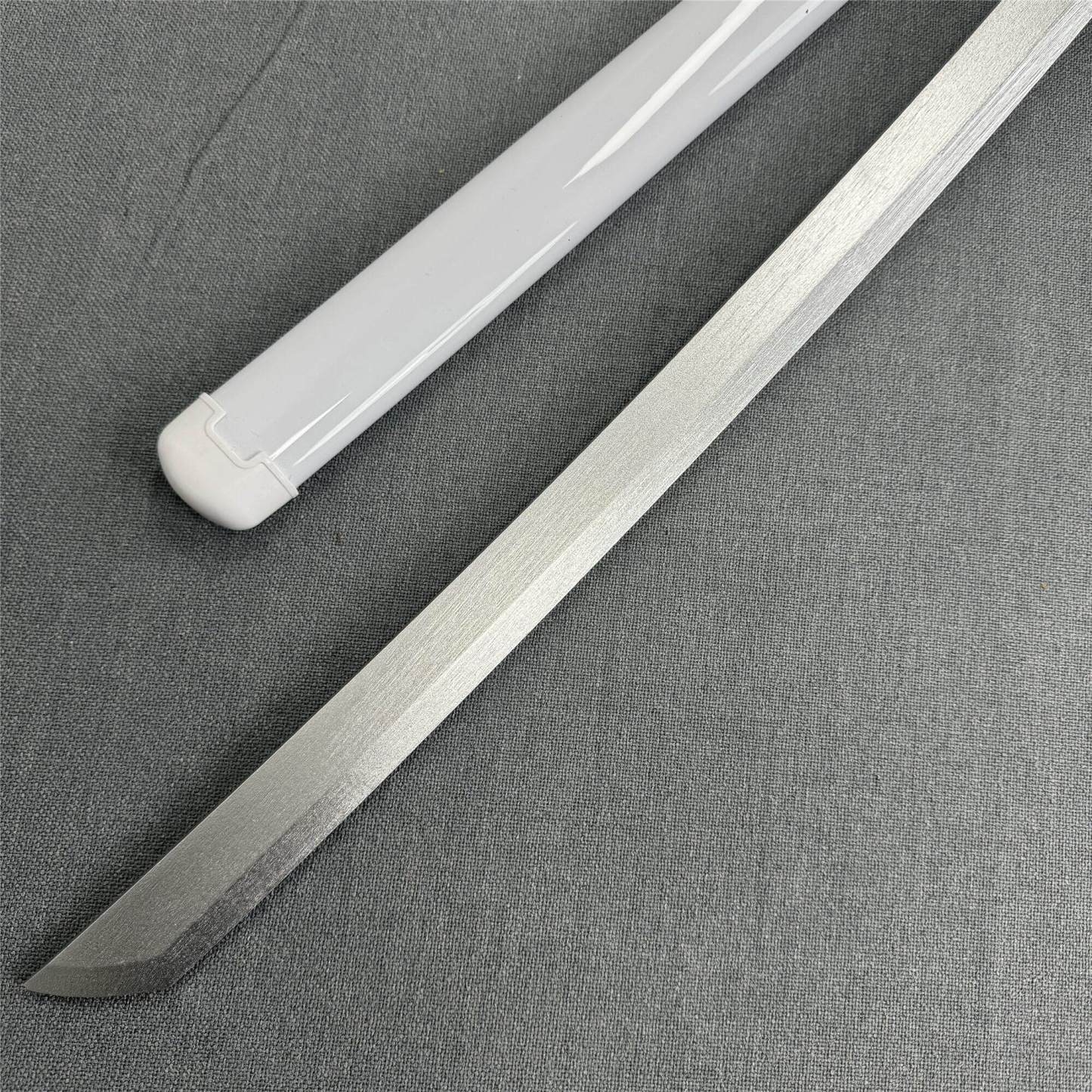 Close-up of the sharp Kissaki tip and white scabbard of the Kuchiki Unleashed 1045 carbon steel katana.