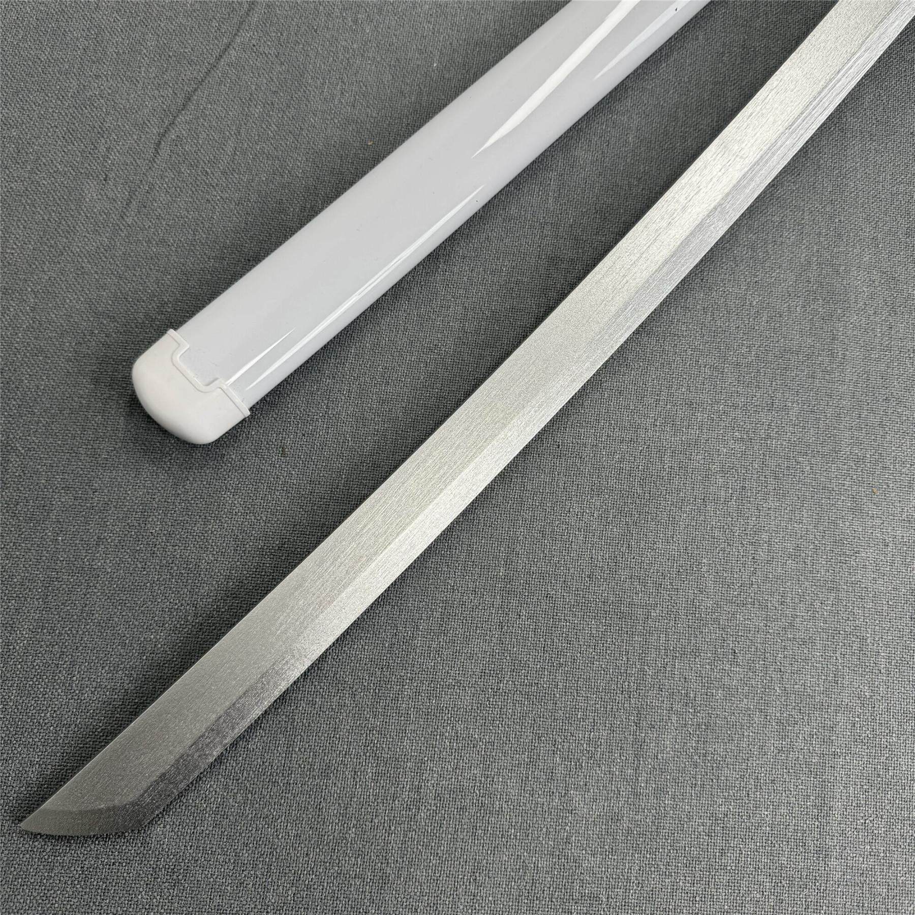 Close-up of the sharp Kissaki tip and white scabbard of the Kuchiki Unleashed 1045 carbon steel katana.