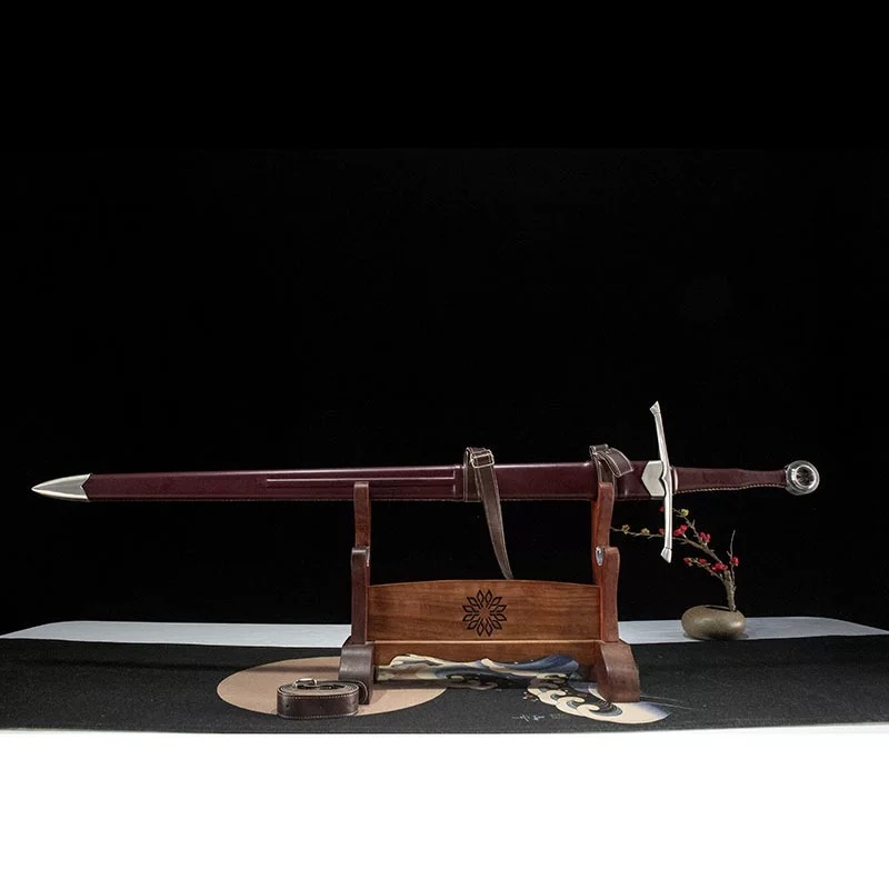 Medieval longsword with leather scabbard displayed on a wooden stand, side profile view.