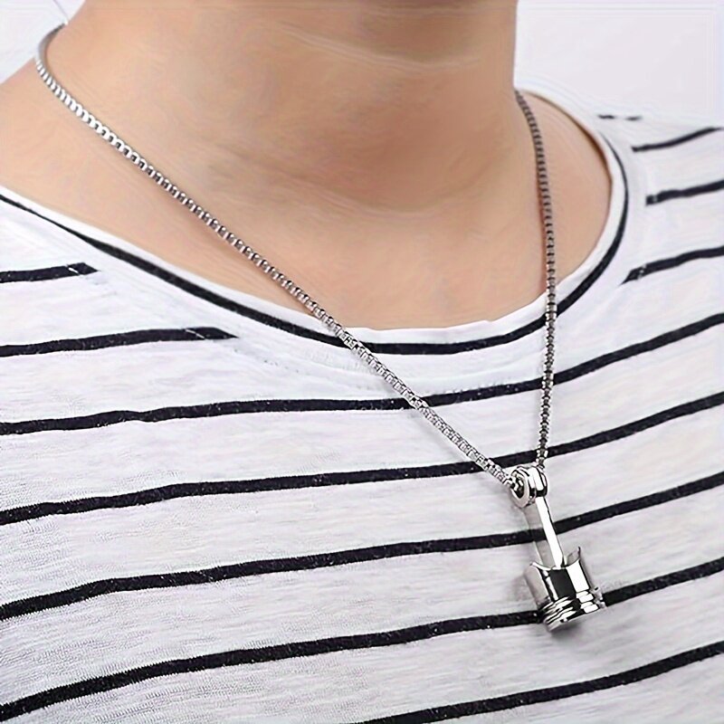 A man wearing a silver motorcycle piston pendant necklace over a striped t-shirt for a casual biker look.