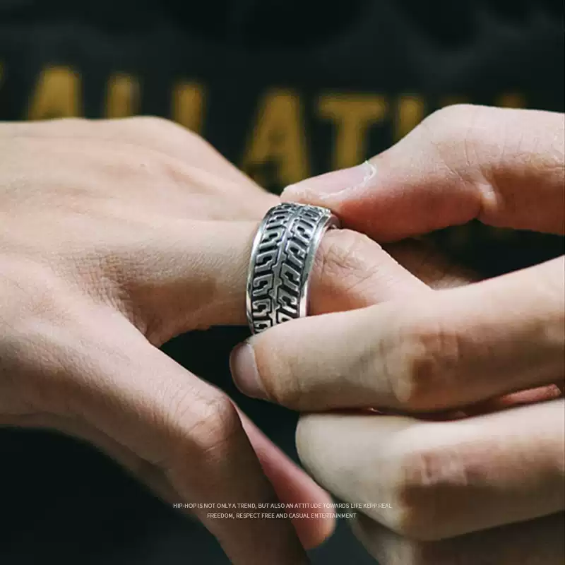 A man wearing the silver motorcycle tire tread ring and spinning the outer band with his fingers.