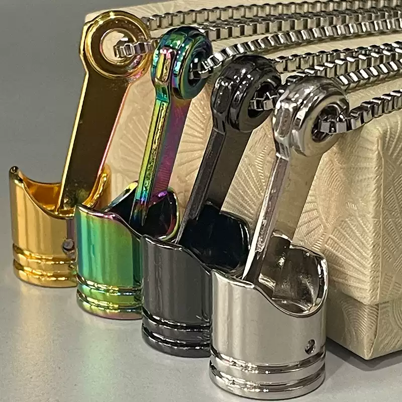 A collection of motorcycle piston necklaces in four different colors including gold, rainbow, black, and silver.