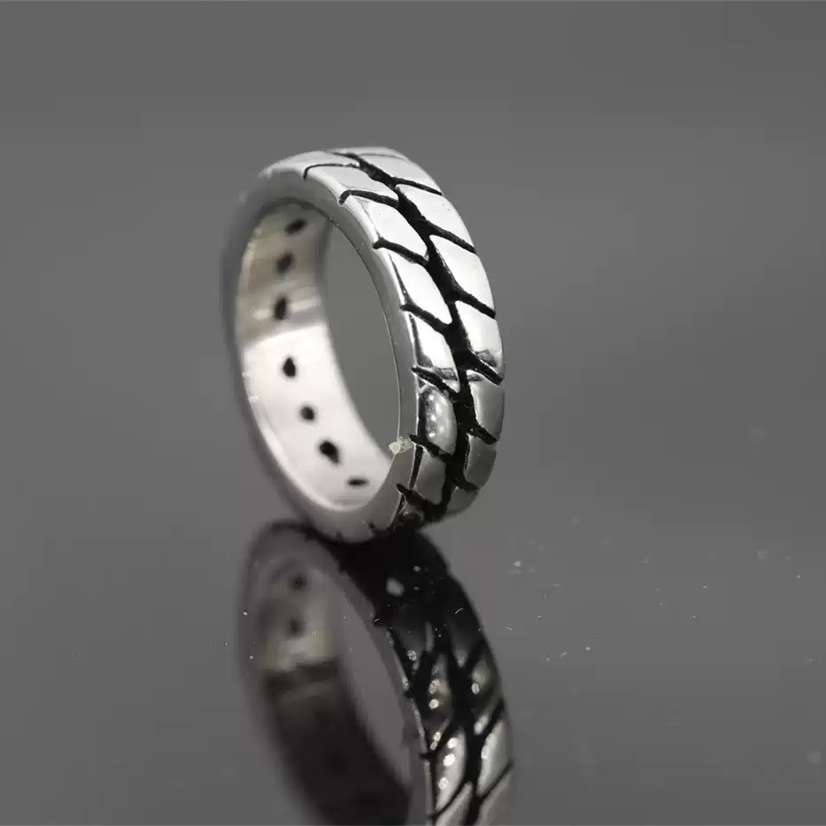 Side angle view of a silver motorcycle tire ring showing the thickness of the band and inner design detail on a black surface.