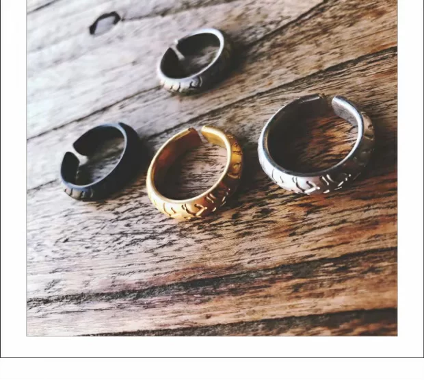 Four different colors of adjustable motorcycle tire tread rings including gold, black, silver, and antique silver arranged on a wooden background.