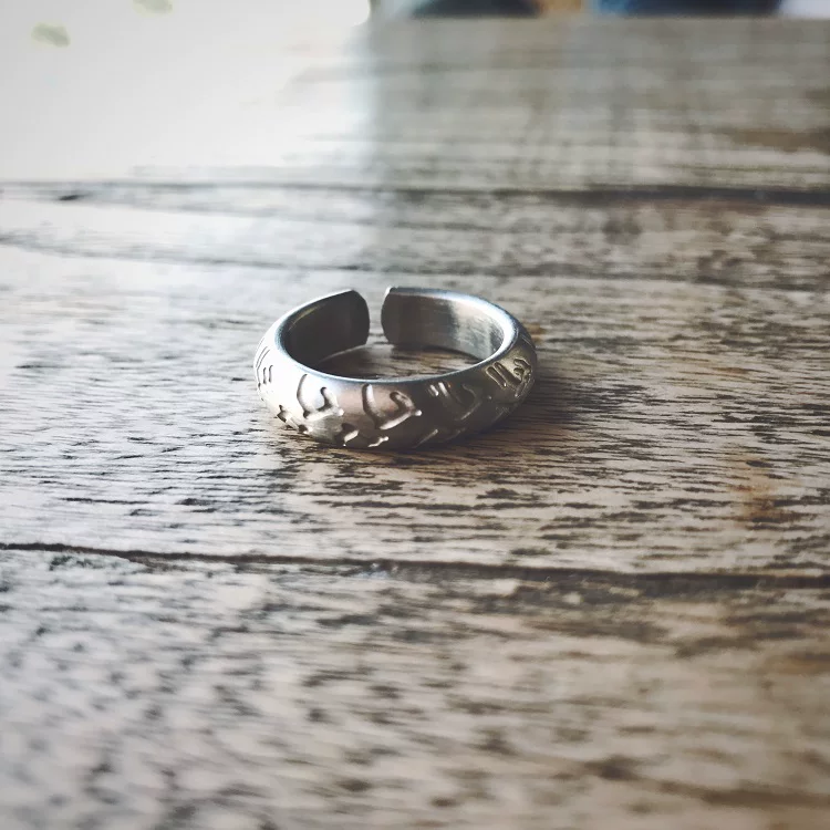 A polished shiny silver stainless steel motorcycle tire tread ring for bikers on a wooden background.