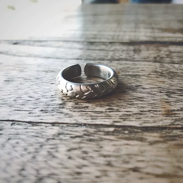 A polished shiny silver stainless steel motorcycle tire tread ring for bikers on a wooden background.