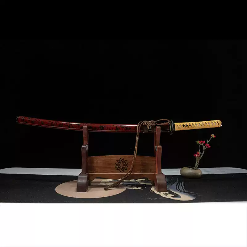 Full view of a sheathed Rurouni Kenshin katana with a red and black lacquered scabbard on a wooden display stand.