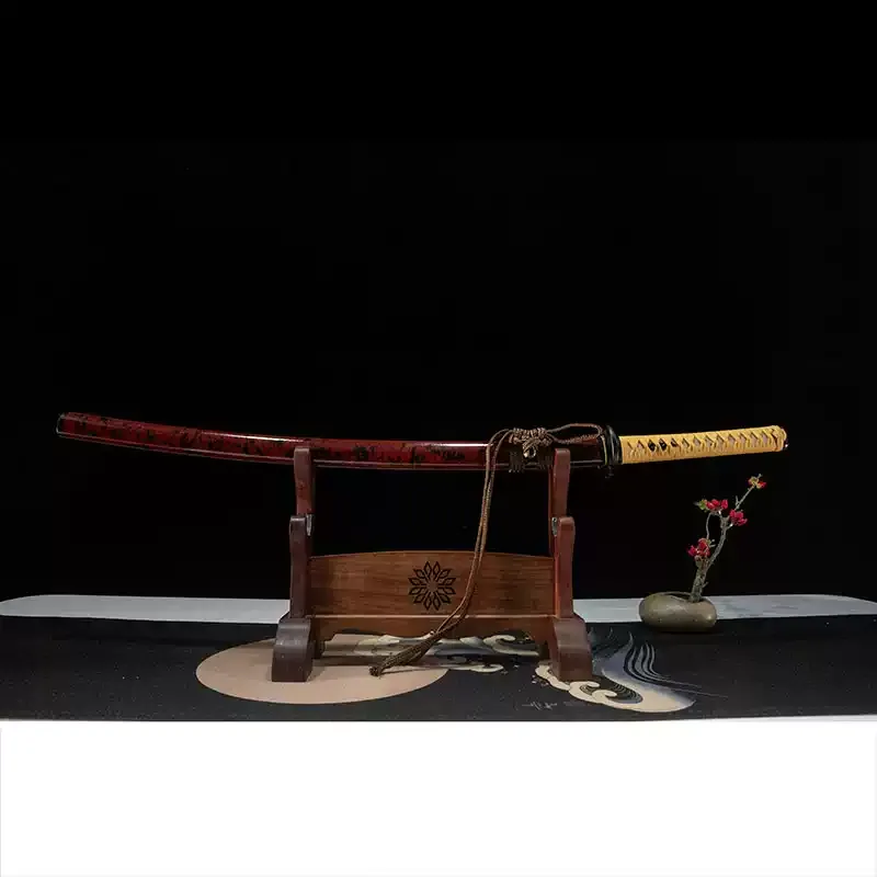 Full view of a sheathed Rurouni Kenshin katana with a red and black lacquered scabbard on a wooden display stand.