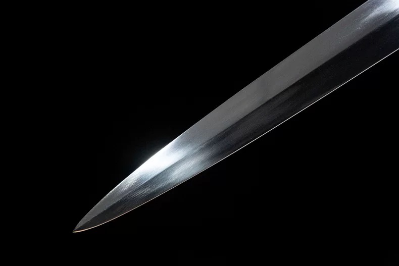 Macro shot showing the sharpness and precise finish of the hand-forged 65 manganese steel longsword blade tip.