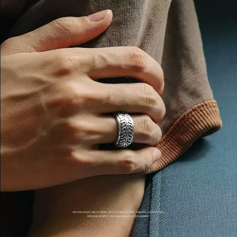 Close-up of a man's hand wearing the silver motorcycle tire tread band ring in a casual setting.