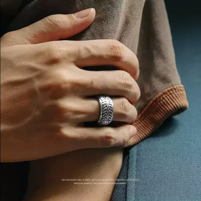 Close-up of a man's hand wearing the silver motorcycle tire tread band ring in a casual setting.
