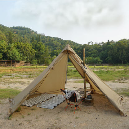 An open tan pyramid hot tent showing the full interior camping setup, including a portable wood stove, stove pipe, and a camping chair.