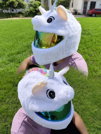 White Unicorn motorcycle helmet cover with a rainbow braided mane and a silver horn, shown on a rider in a sunny outdoor setting.