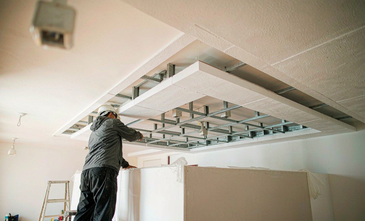 Craftsman installing a plasterboard false ceiling with cove lighting