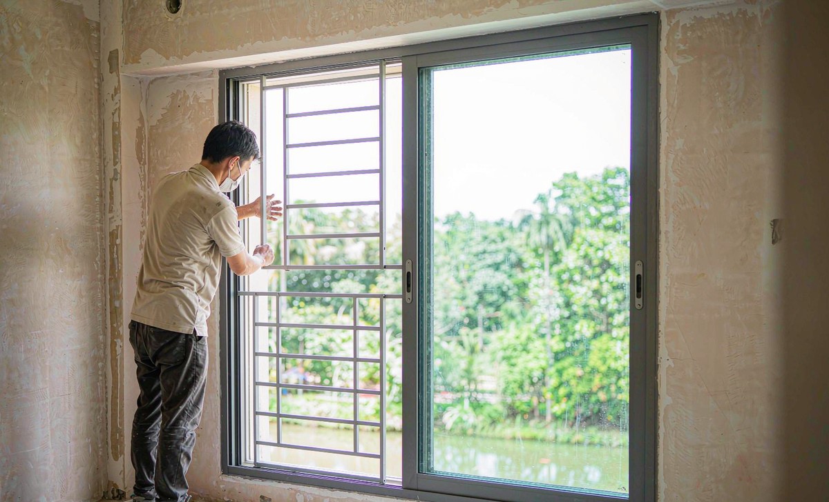 Worker fitting a slim aluminium sliding window with safety grille