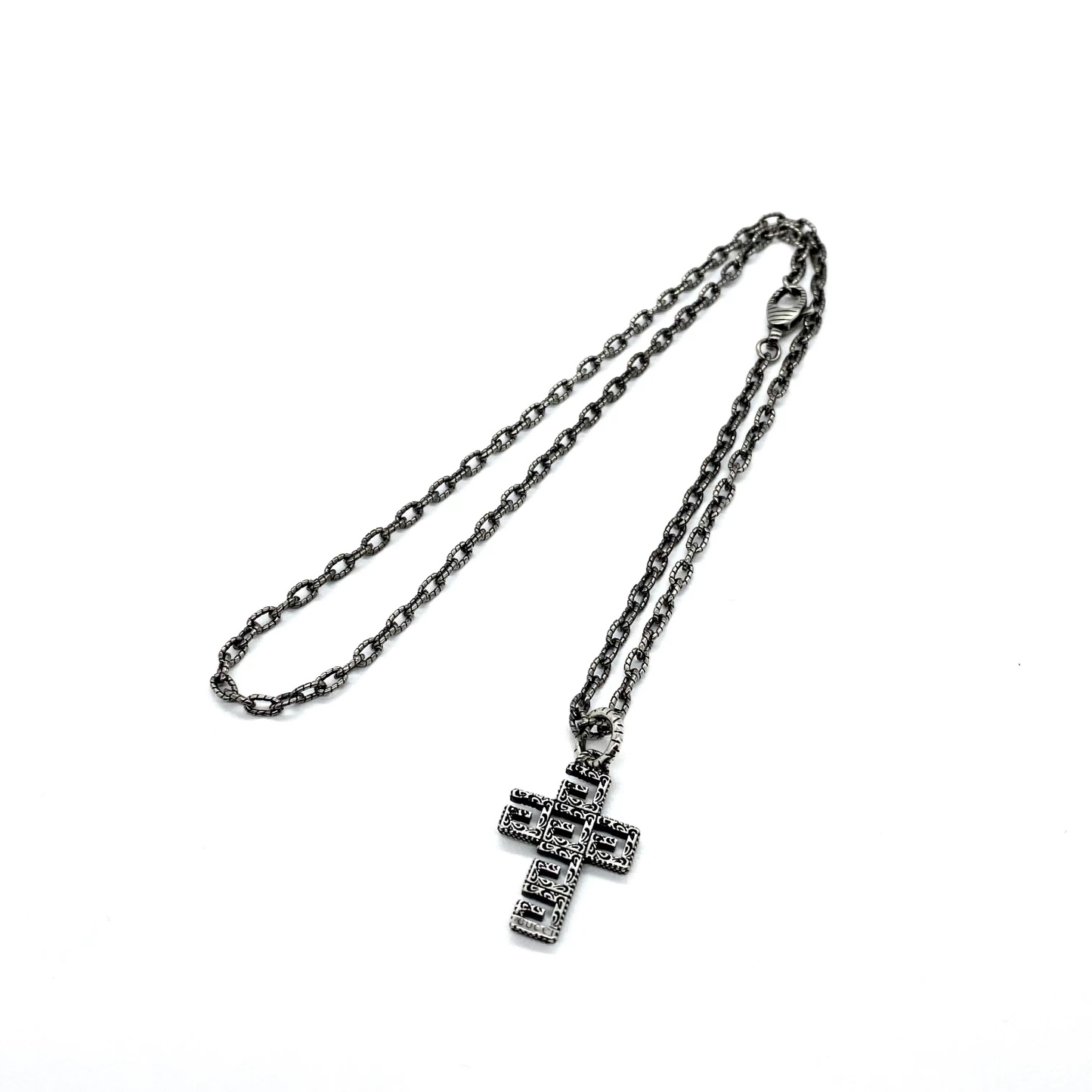 Gucc* の G 文字入りの十字架型の透かし彫りネックレス