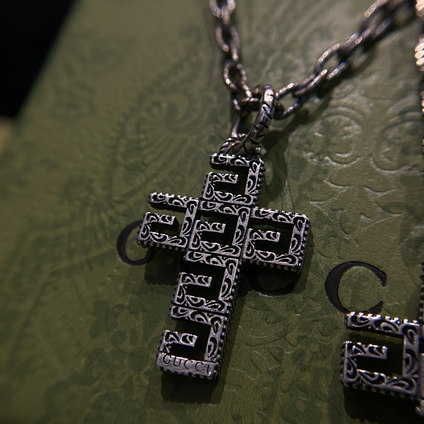 Gucc* の G 文字入りの十字架型の透かし彫りネックレス