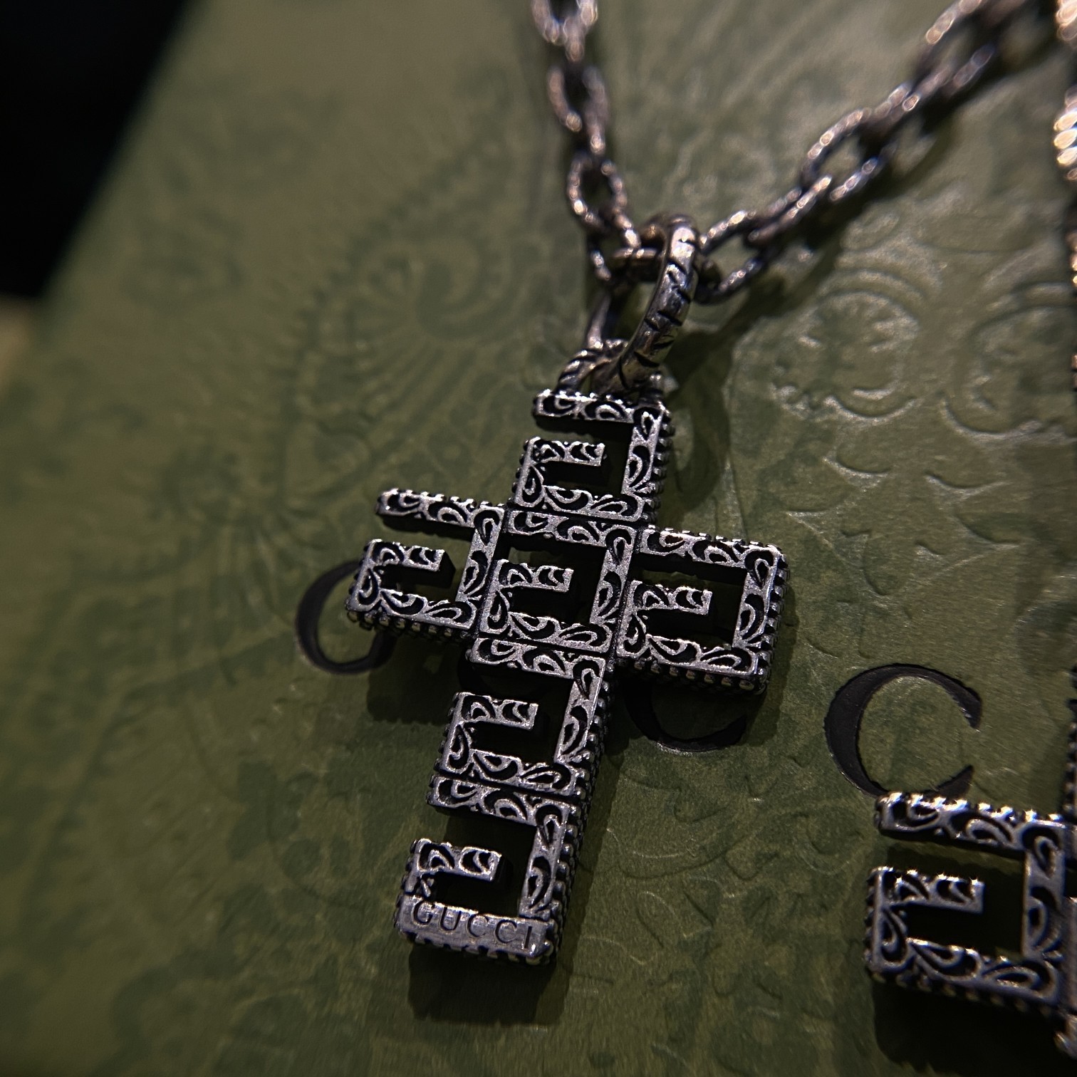 Gucc* の G 文字入りの十字架型の透かし彫りネックレス