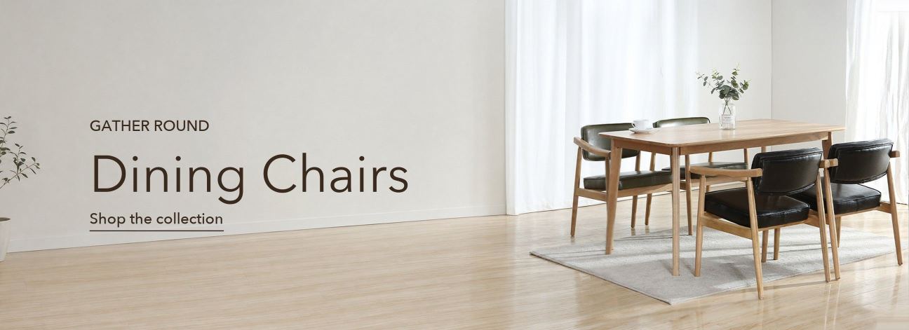 Four black leather and oak wood dining chairs around a light wood dining table by a sunlit window, Lighom dining chairs collection