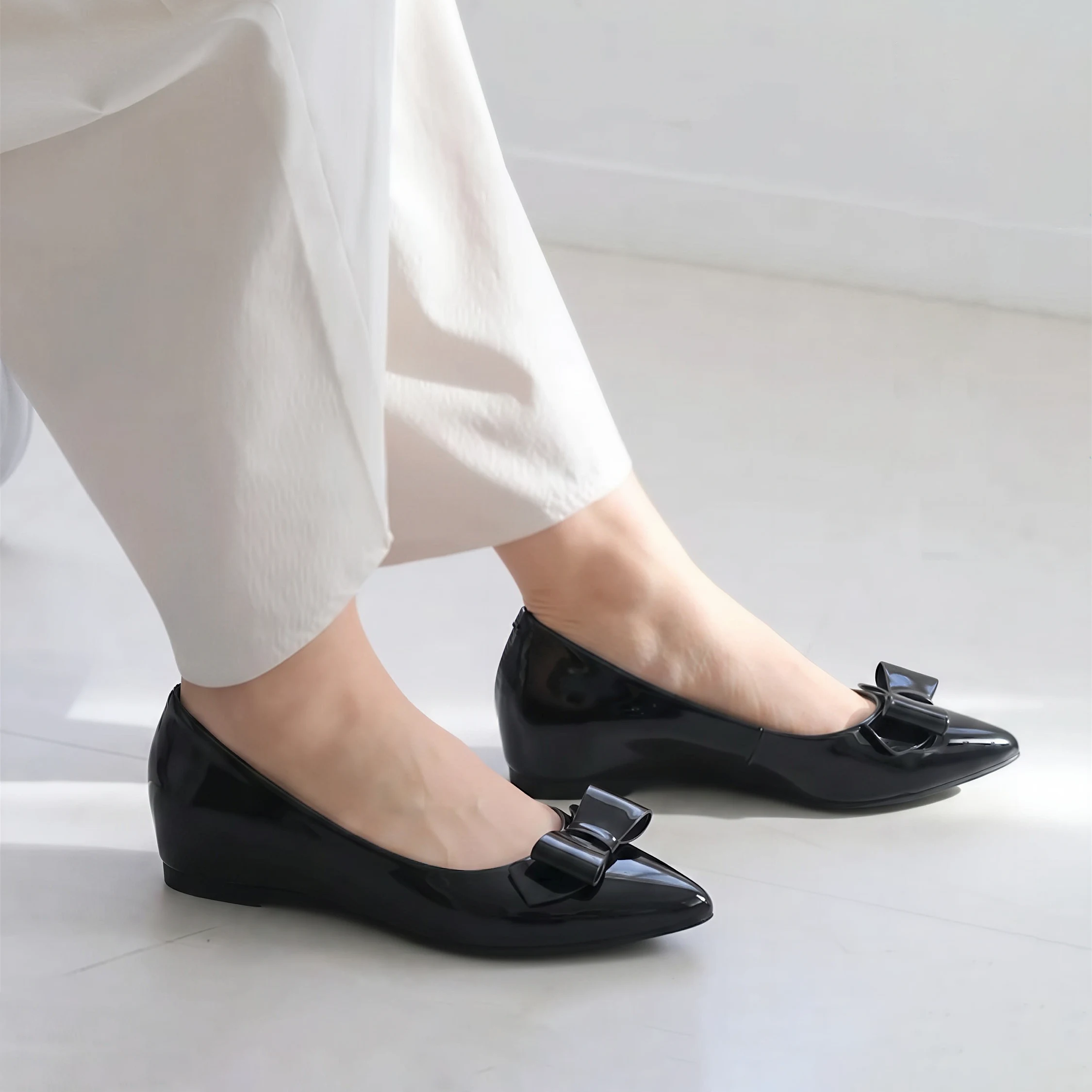 ブラックのリボン付きポインテッドトゥパンプスを白パンツに合わせた着用イメージ