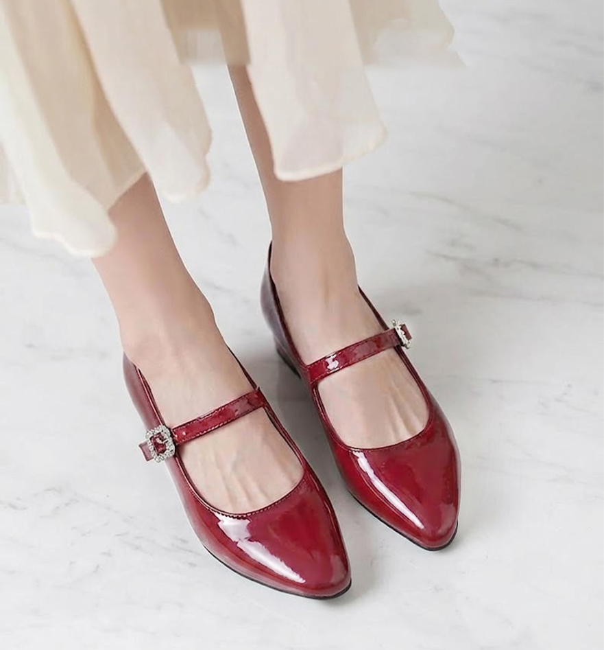 レッドのマリージェーンパンプスを履いた足元のアップ。エナメルの艶がコーディネートのアクセントに。パーティーやデートなど華やかなシーンに映える一足。