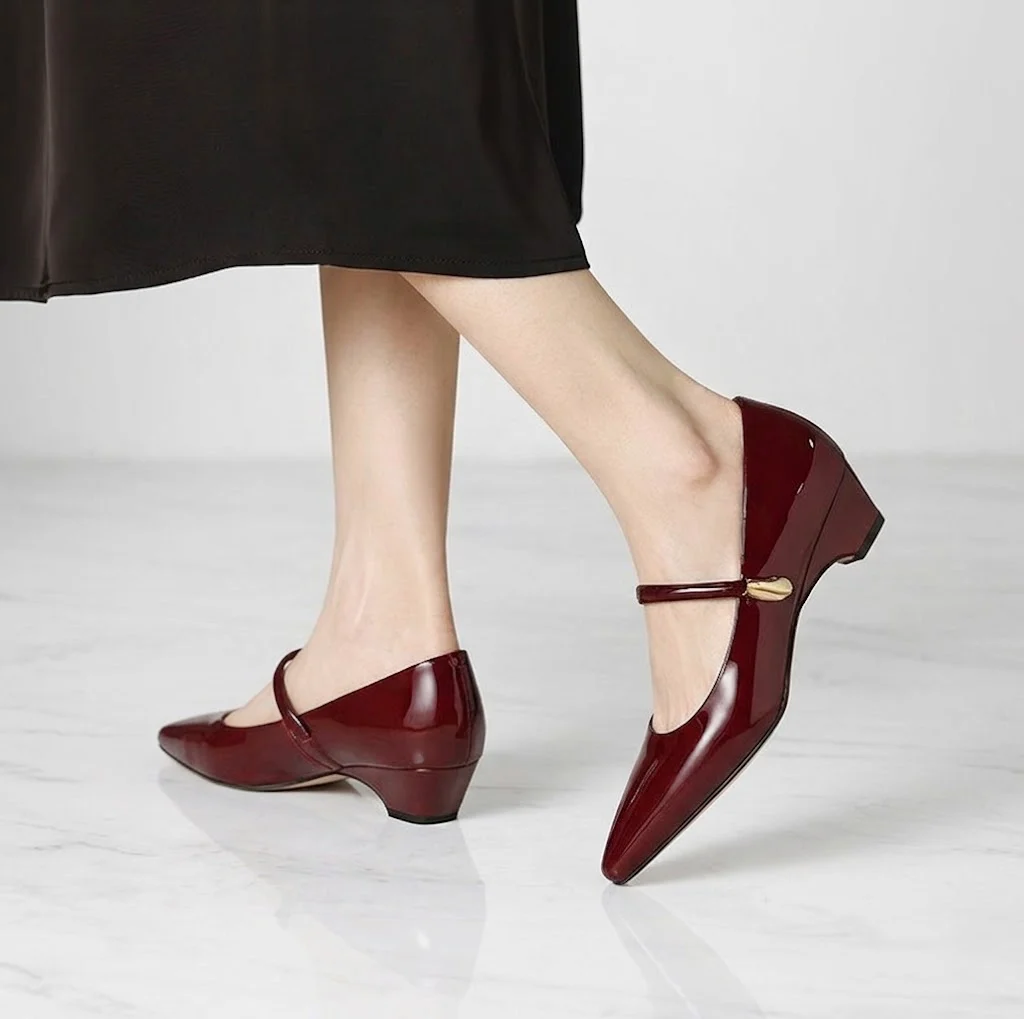 黒のスカートに映えるワインレッド（ボルドー）のエナメルパンプス。横から見ても美しいシルエットと、しっかり足をホールドしてパカパカしないストラップ