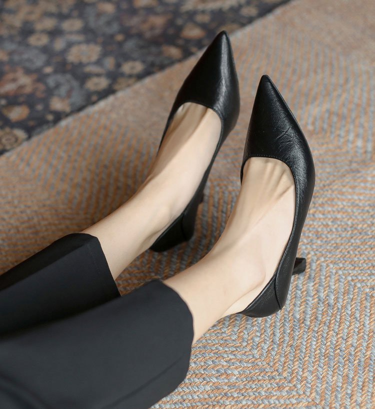  足先を細く長く見せるシャープなポインテッドトゥの黒パンプス。履くだけで美脚効果があり、パンツスタイルに合わせやすい万能な仕事靴