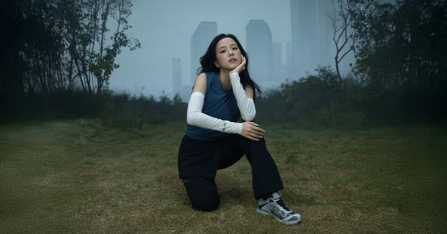 JISOO standing in open ground in front of a misty city