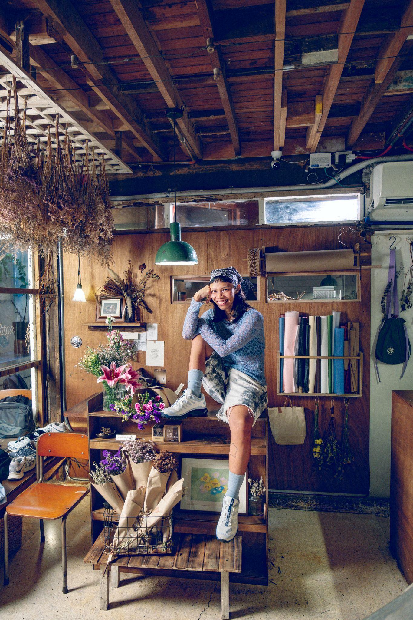 Soleil Ignacio seated in her studio surrounded by flowers and creative materials
