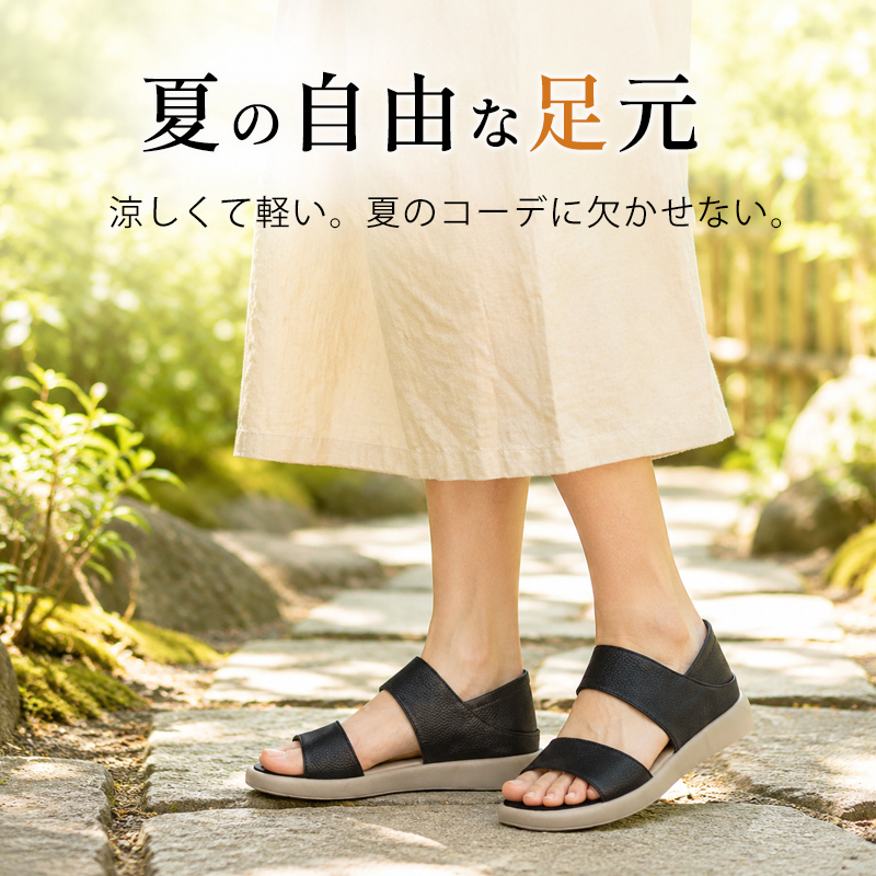 ブラックの2wayコンフォートサンダルとロングスカートの石畳の小道を歩く夏コーデ