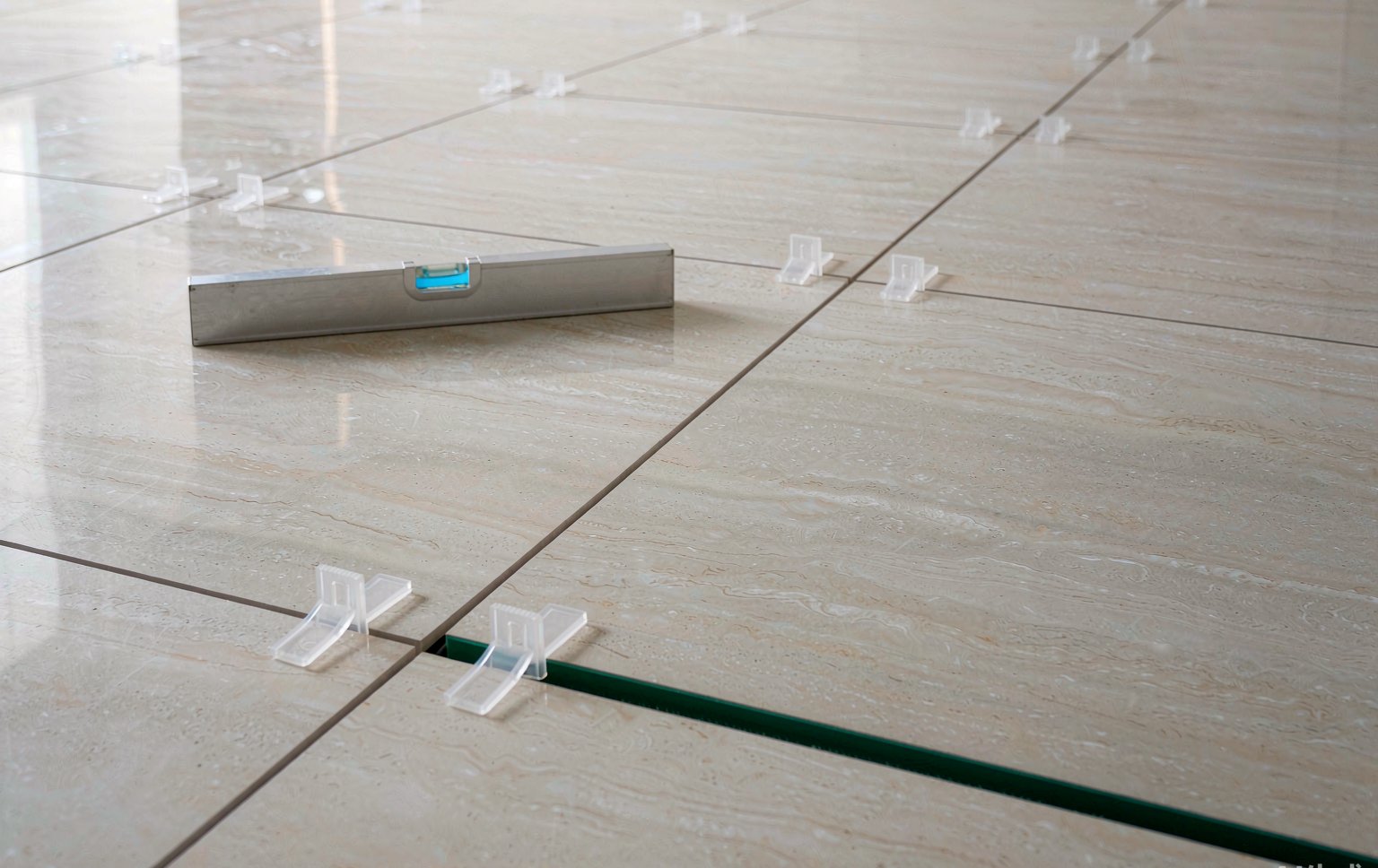 Large-format porcelain tiles laid straight with levelling clips and a spirit level