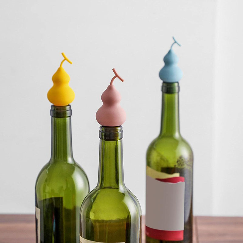 multicolor matte hulu gourd silicone wine bottle stopper inserted on green wine bottles wooden table scene