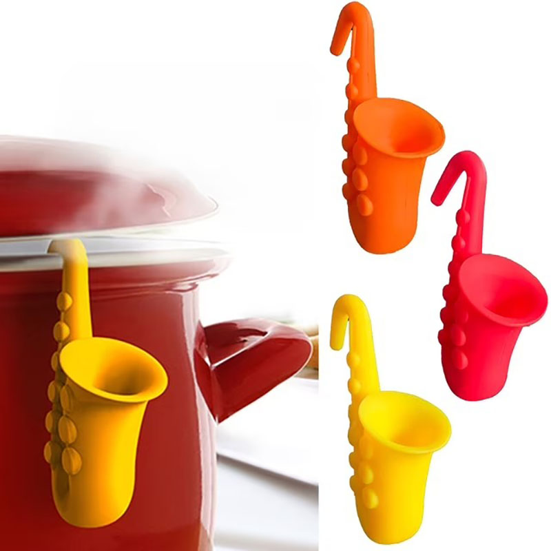 yellow saxophone silicone steam releaser clipped on red enamel cooking pot white background kitchen scene
