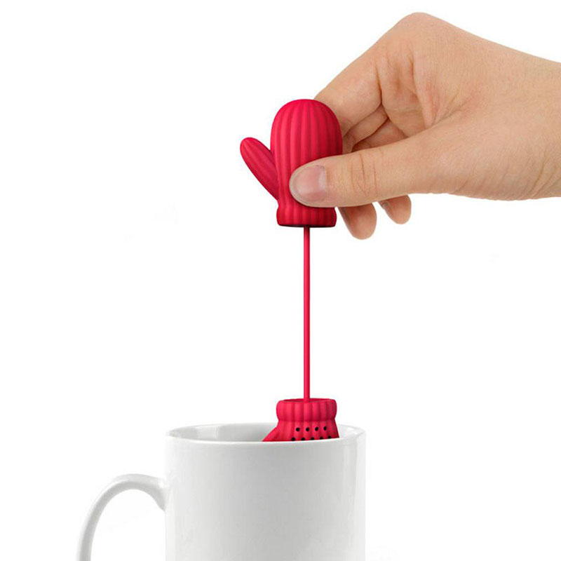 mitten tea infuser steeping black tea beside winter red berry branches