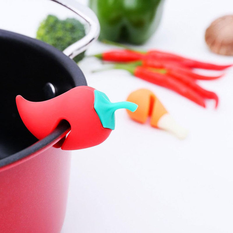 red chili pepper silicone steam releaser clipped on red cooking pot white background kitchen scene