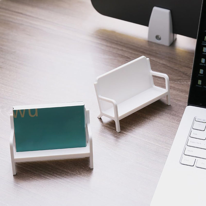 two white mini park bench plastic card holders on wooden office desk scene white background