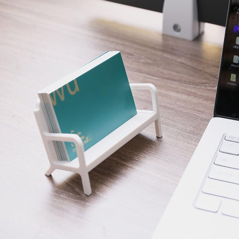 bench card stand displaying business card beside laptop desktop display