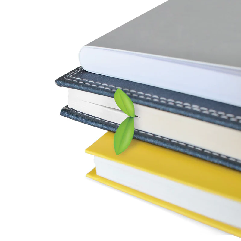 green sprout leaf silicone bookmark inserted between stacked notebooks white background product shot