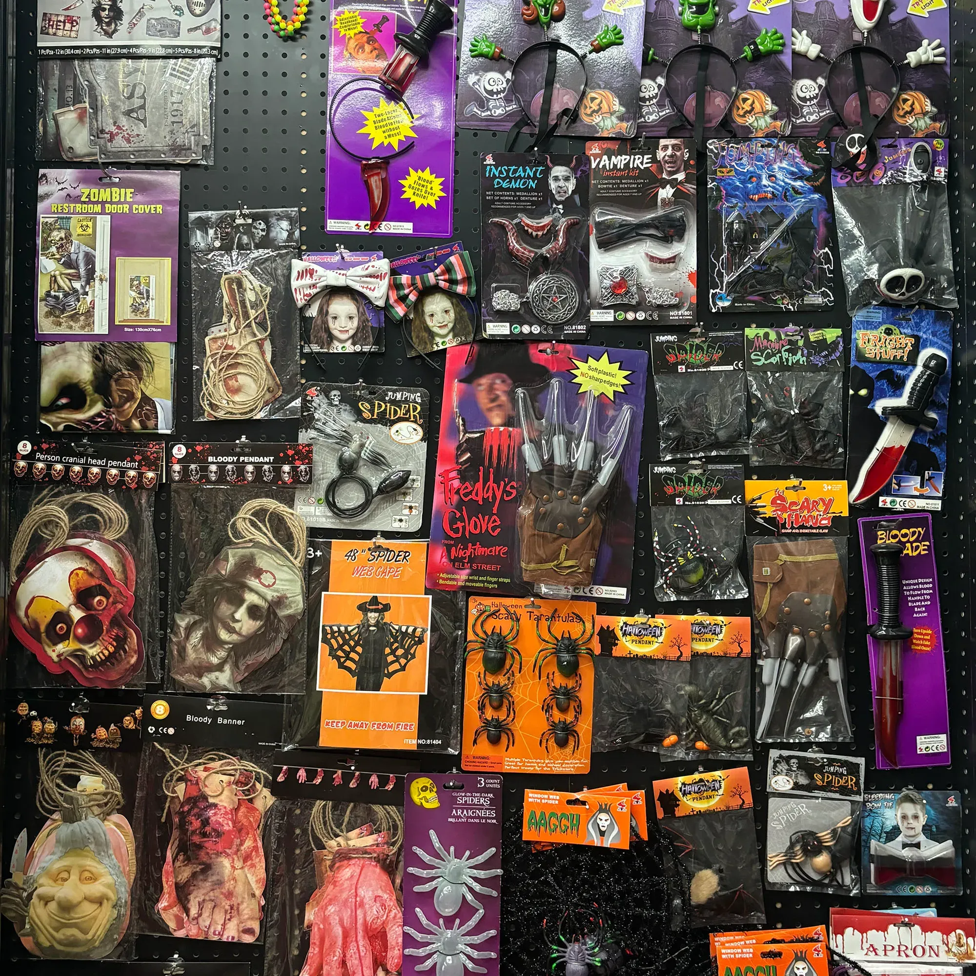 Assorted halloween scary costume props display, vampire fangs, fake knives, horror gloves, spooky hanging ornaments for haunted house party decorations bulk
