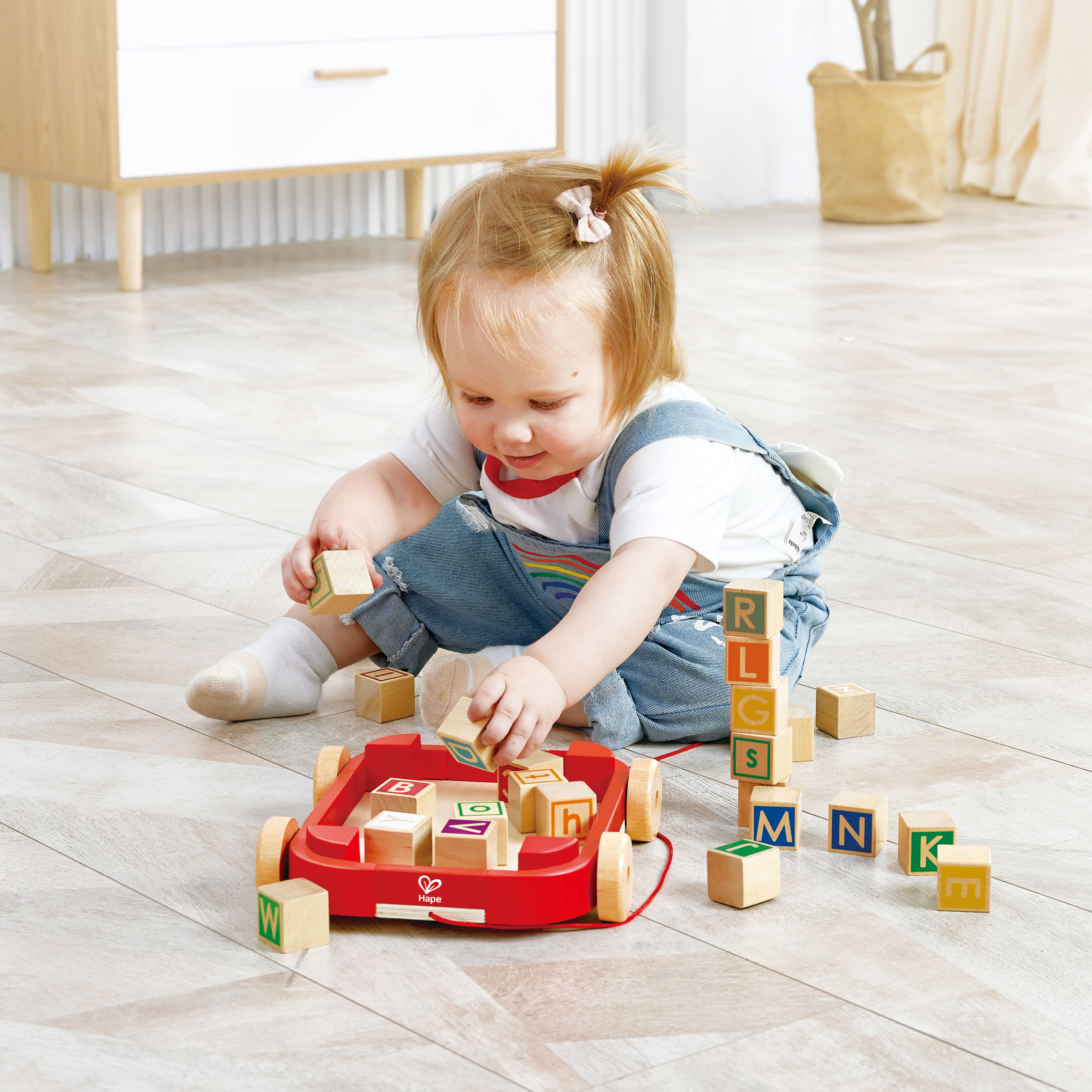 親子互動遊戲中，孩子拉動裝滿積木的木製拖車，鍛鍊大肌肉協調