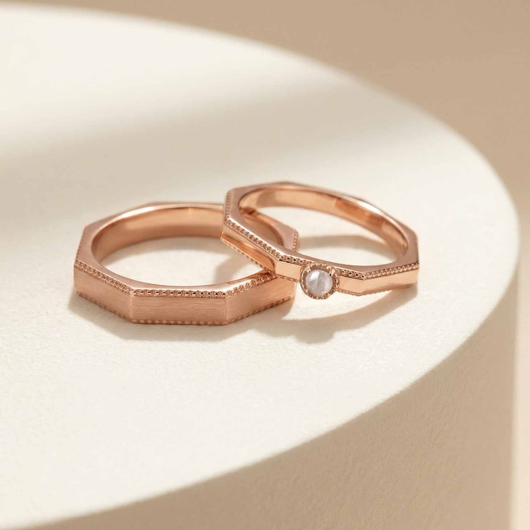 DIABOND 復古玫瑰金色手工結婚對戒交錯展示。戒指採獨特的八角形幾何設計，邊緣飾有精緻的古典滾珠邊 (Milgrain edge)。右側女戒頂部鑲嵌一顆綠色毛胚天然原鑽 (Rough Diamond)。