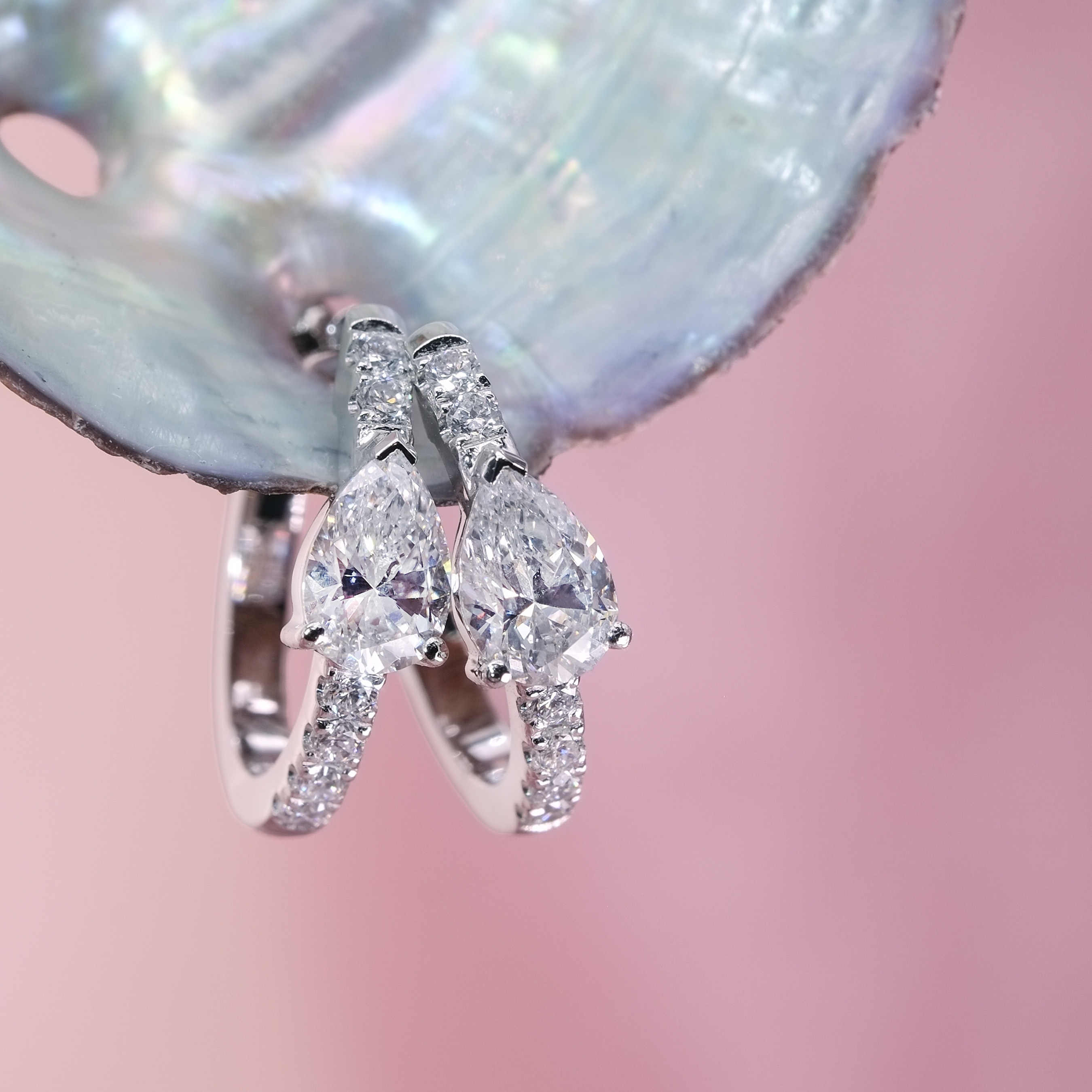 Close up of pear shape lab grown diamond huggie earrings showing VVS clarity and pave setting details