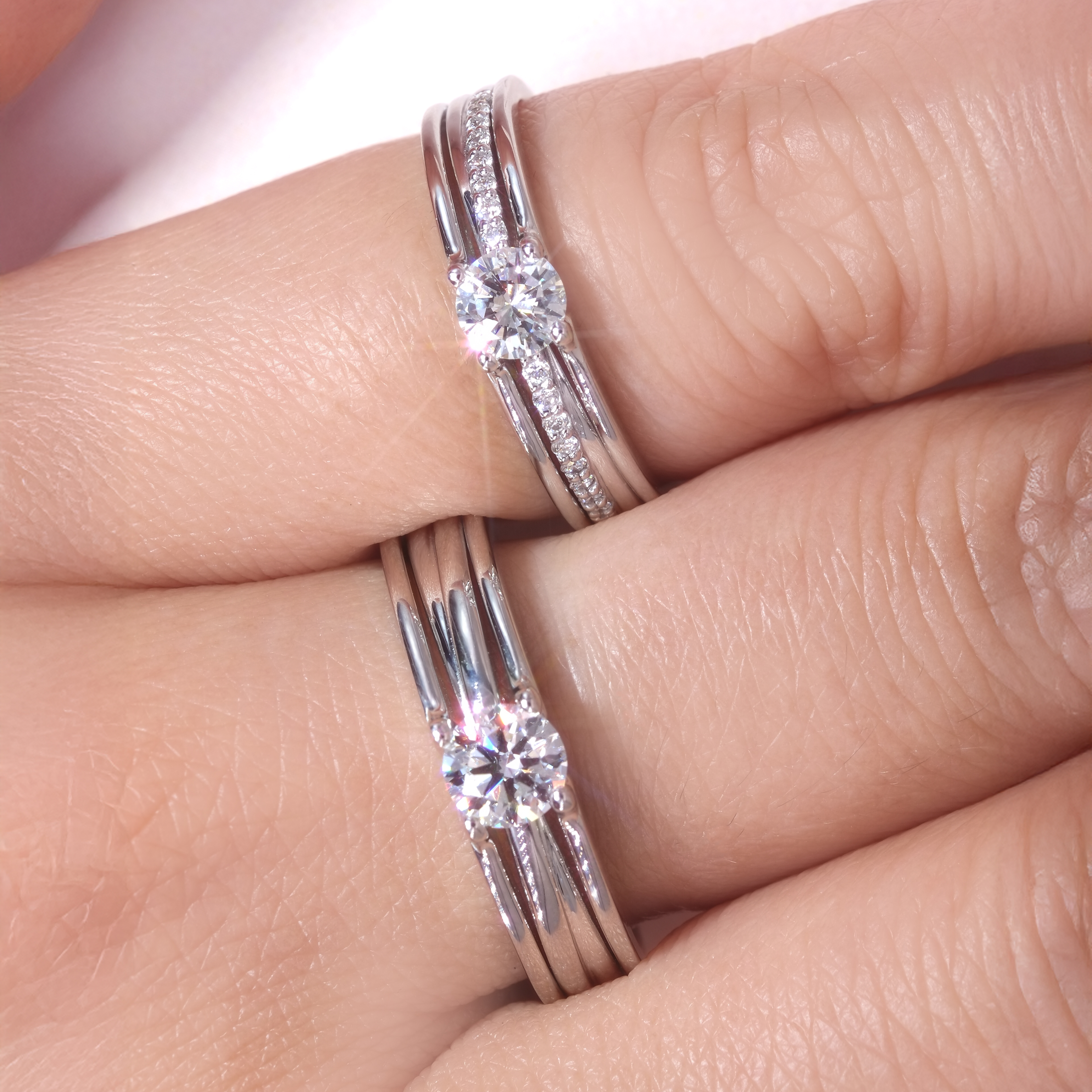 男女模特兒佩戴 DIABOND 天然鑽石結婚對戒牽手近拍。女方佩戴玫瑰金色多層次線條戒指，鑲嵌 0.4ct 主鑽；男方佩戴銀白色同款寬版對戒，鑲嵌 0.5ct 主鑽，盡顯立體層次與份量感。