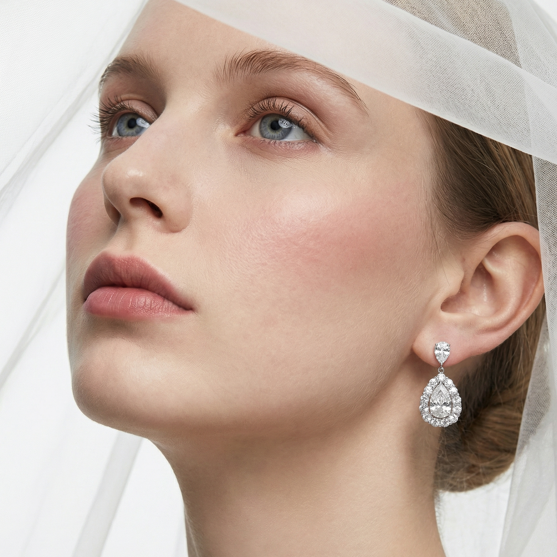 模特兒佩戴淚之水滴梨形培育鑽石耳環的實穿展示。約 22.2mm 的懸垂長度 (Drop Design) 隨著步伐輕盈搖曳，完美拉長了頸部與下顎線條。水滴形主石結合璀璨的圍鑲光環，在耳畔散發出猶如晨露般純淨高貴的光芒，是新娘婚嫁或出席晚宴的完美珠寶。