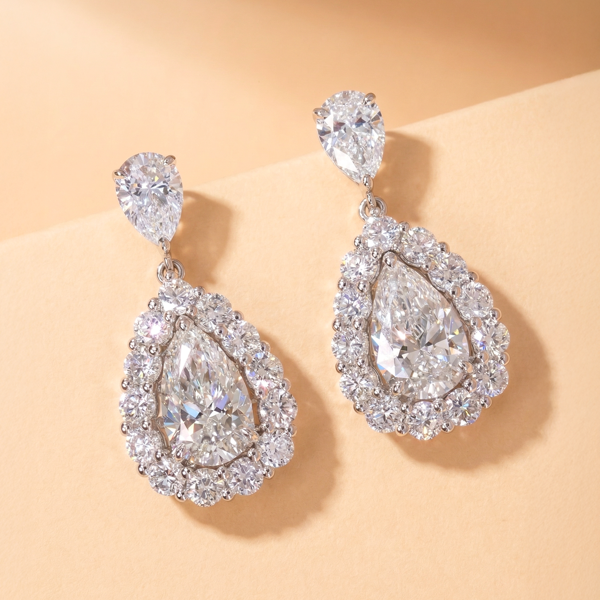 DIABOND 淚之水滴梨形培育鑽石吊墜耳環平放特寫。採用 18K 白金打造，耳環頂部以一顆精緻的水滴鑽石連接著下方的主體。下方為每邊 1 克拉（F 色、VS 淨度）的梨形切割 (Pear Cut) 主石，外圍環繞著一圈璀璨的密釘鑲嵌光環 (Halo Setting)，視覺效果極致奢華放大。附雙 IGI 證書。

