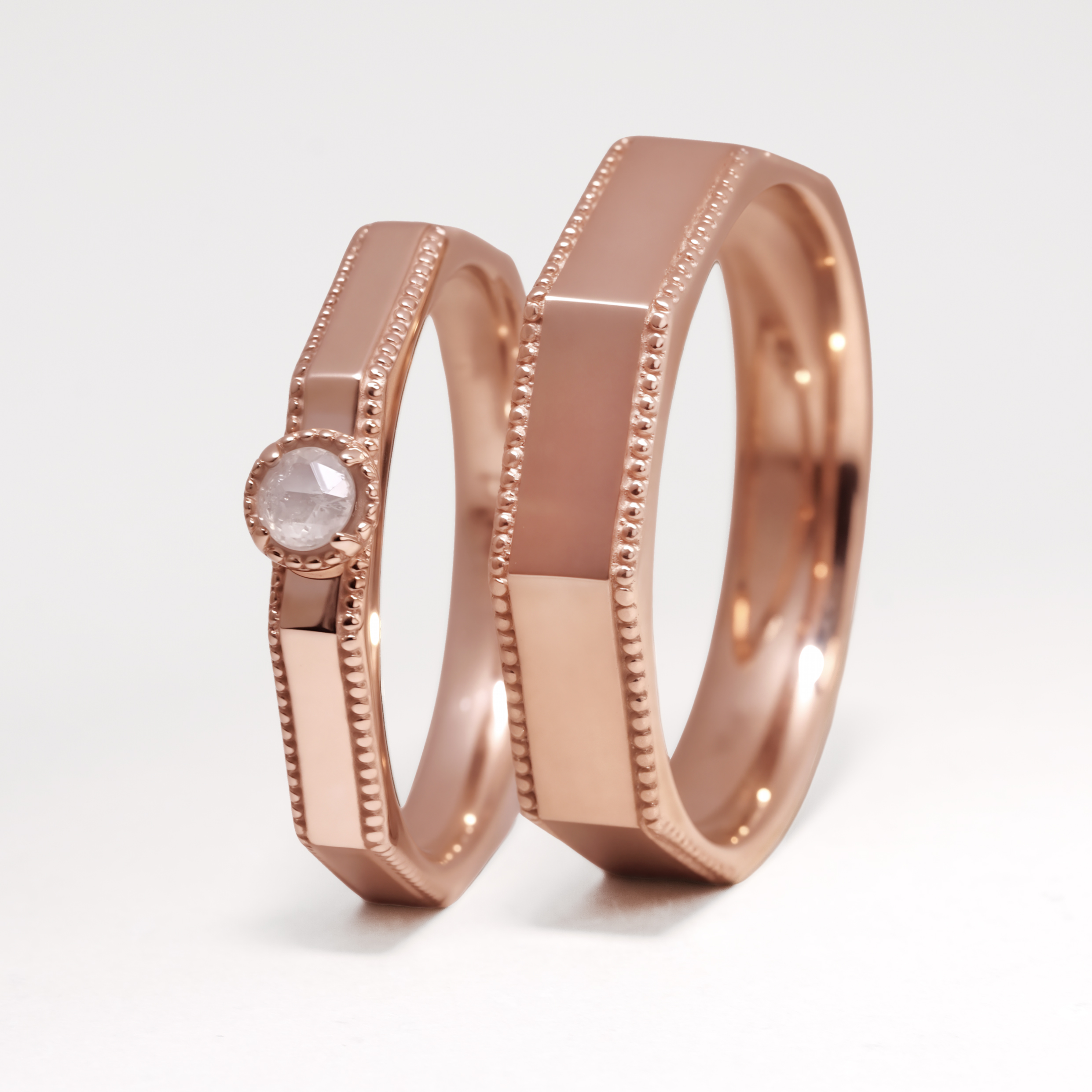 DIABOND 復古玫瑰金色手工結婚對戒交錯展示。戒指採獨特的八角形幾何設計，邊緣飾有精緻的古典滾珠邊 (Milgrain edge)。右側女戒頂部鑲嵌一顆綠色毛胚天然原鑽 (Rough Diamond)。