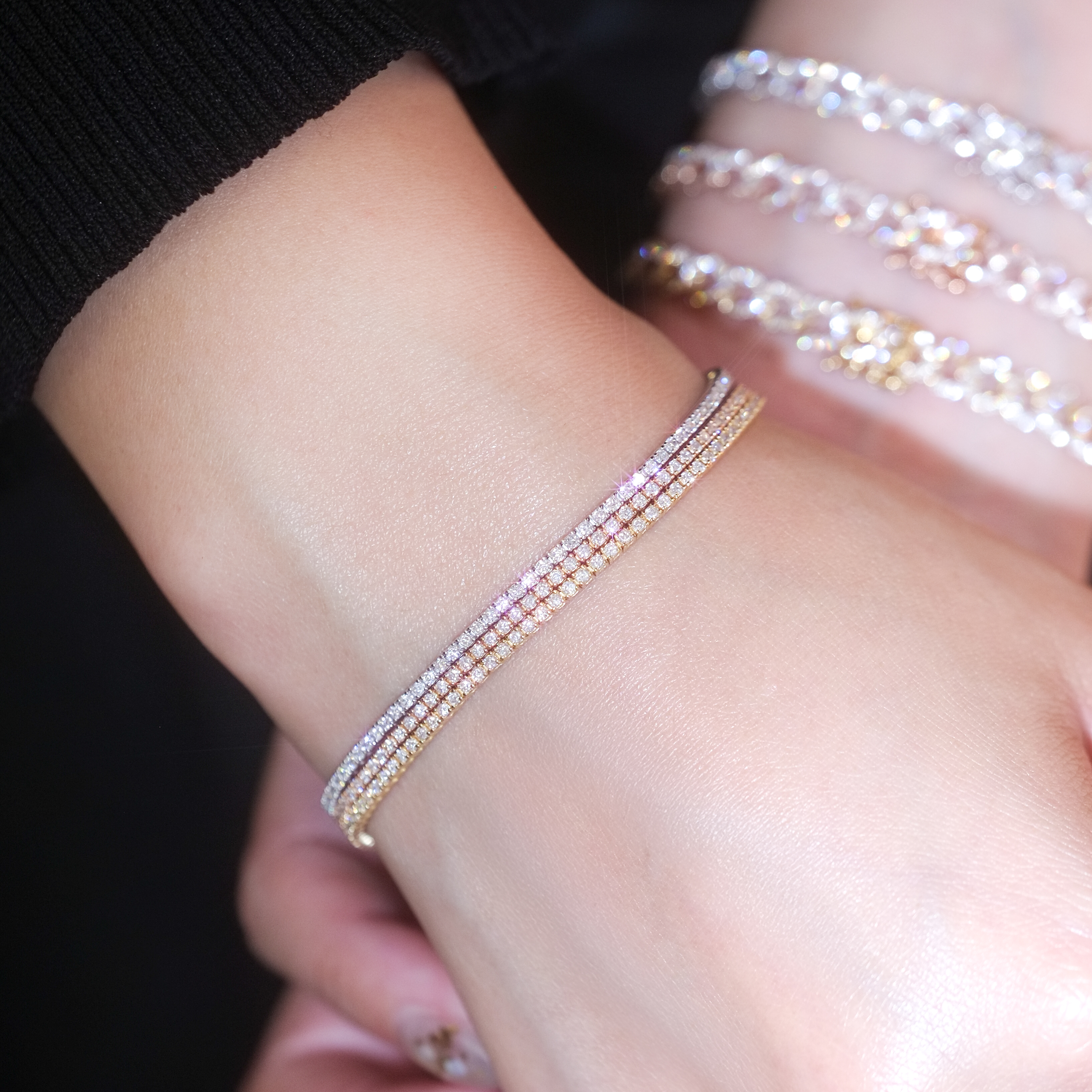 Model wearing stack of three 1.3mm dainty lab grown diamond tennis bracelets in white, yellow, and rose gold.