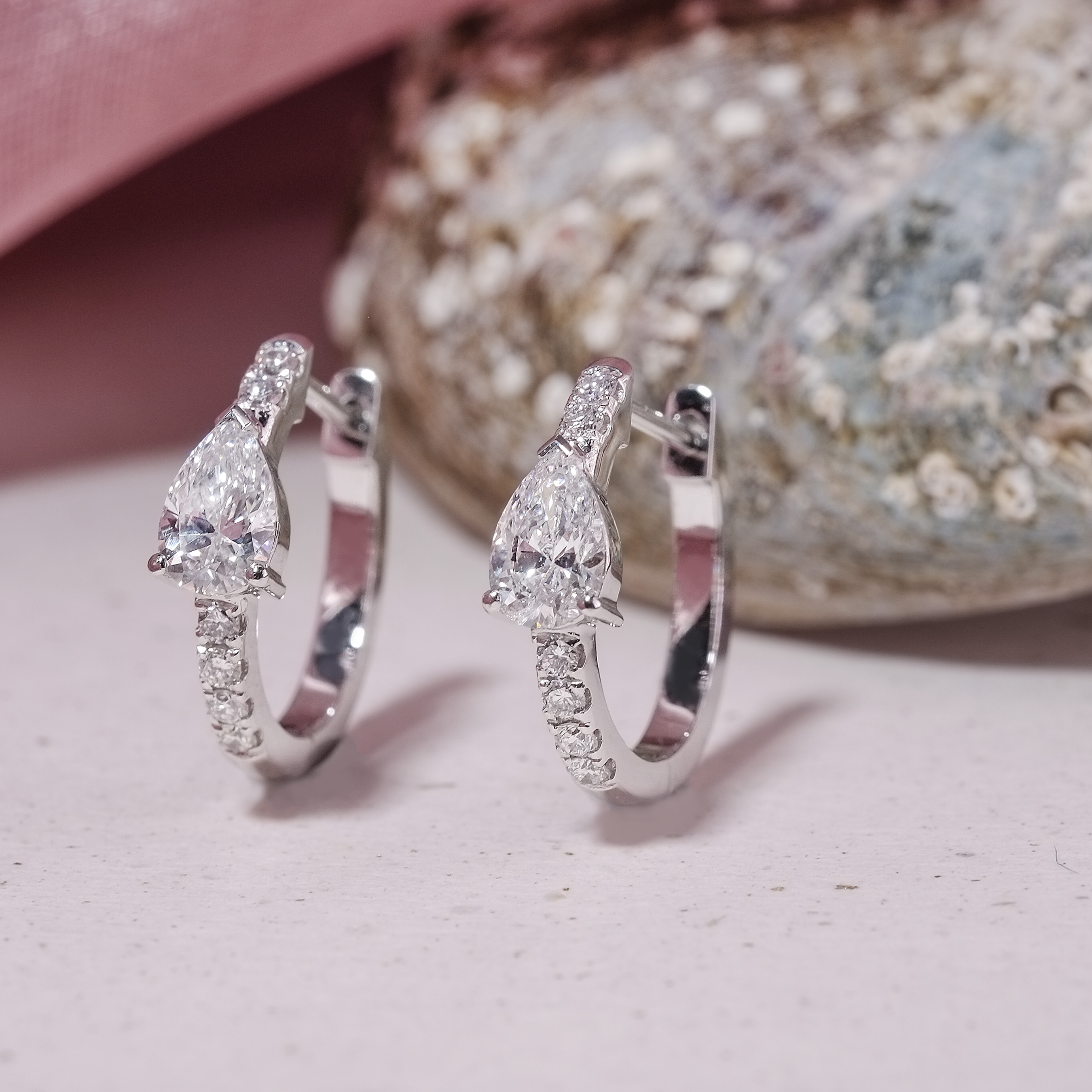 Close up of pear shape lab grown diamond huggie earrings showing VVS clarity and pave setting details
